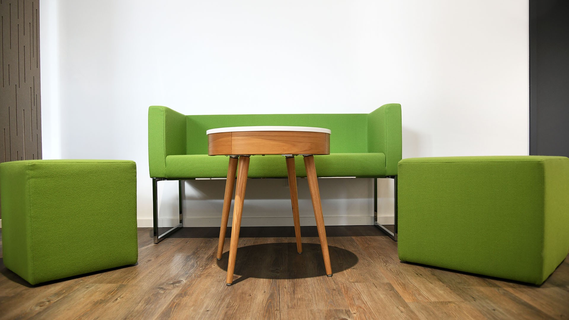 Foto: Grünes Sofa mit zwei Hockern und Holztisch